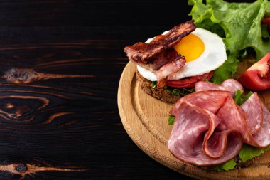 jambonlu ve pastırmalı sandviç koyu ahşap arka planda fotokopi alanı var.