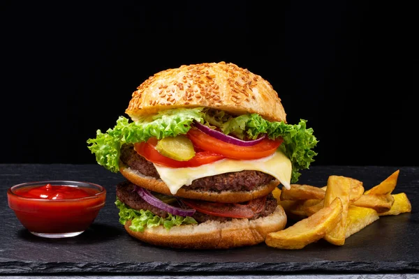 Koyu arkaplanda patates kızartması olan büyük hamburger..