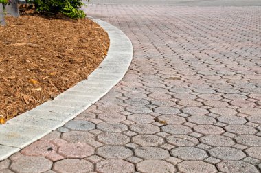 Çocuğun bakışı sekizgen ve square tuğla finişer bitki ve malç kazık gösterilen kenarı boyunca uzanan dikdörtgen tuğla driveway eğri bölümle şeklinde. Sola eğrileri.
