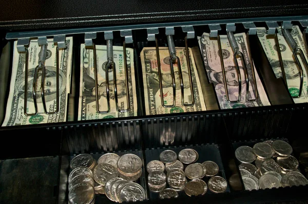 A retail cash drawer in open displaying various types of US currency money and change from cashiers point of view. Grain visible at 100%