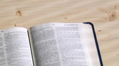 Bir İncil bırakır açık kitap sayfaları tüm dört Gospels leafing ve Saint John durdurma rüzgar tarafından üflenir olarak çapraz gölgeler yapma ışık yumuşak ışınları ile ahşap bir masa üzerine.