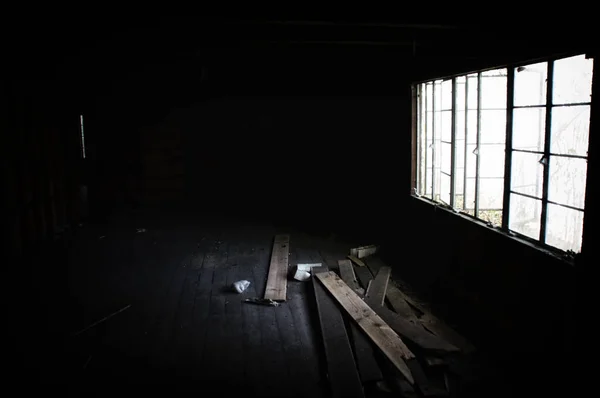 A dark abandoned home illuminated by only the side windows showing debris on floor. noise at 100%