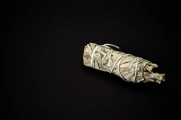A bundle of dried white sage used for smudging on black background used by native americans for cleansing and shamanic ceremonies.