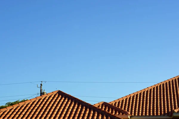 Orange terra cotta rooftop against blue sky with powerlines — Stock Photo, Image