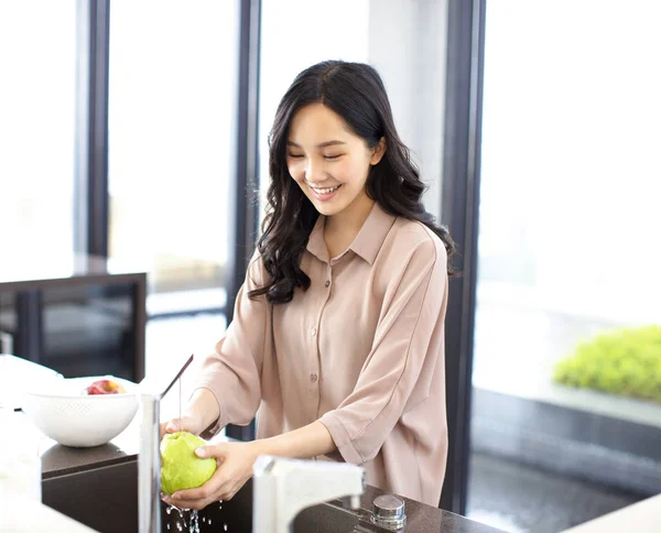 若い女性が台所で果物を洗う — ストック写真