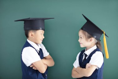 Mutlu erkek ve kız sınıfta mezuniyet şapkalı