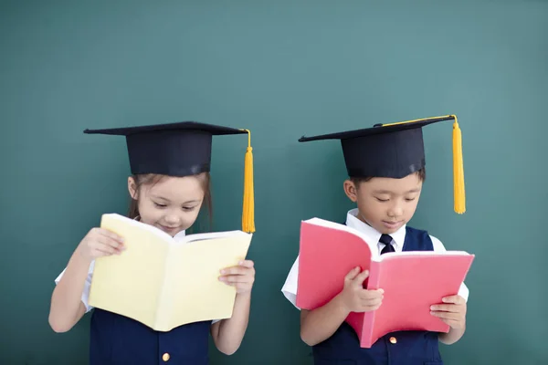 快乐的男孩和女孩在毕业帽和学习 — 图库照片