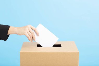 Ballot box with person casting vote on blank voting slip clipart