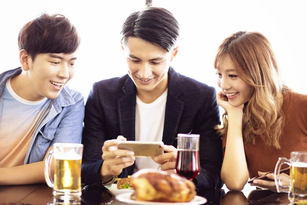 Jóvenes Amigos Viendo Teléfono Inteligente Restaurante —  Fotos de Stock