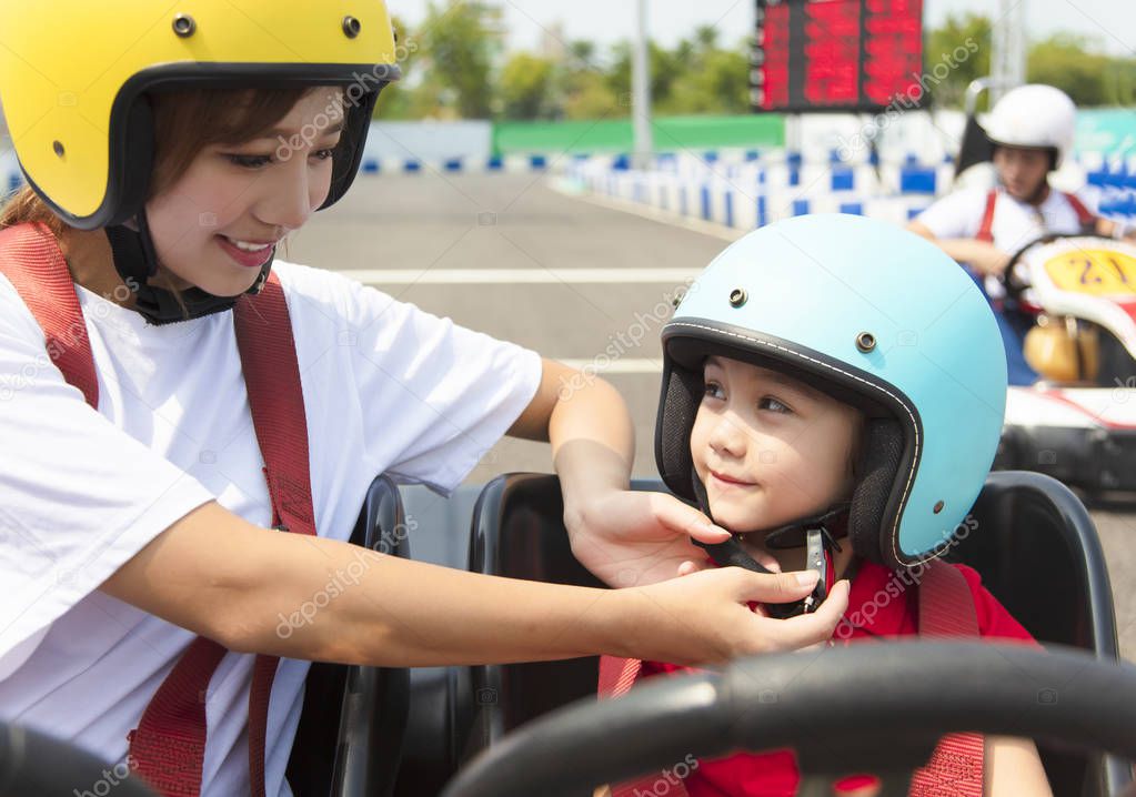 Mother attaching daughters  helmet on go kart race track