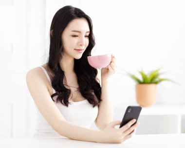 gülümseyen genç kadın oturuyor ve cep telefonu izlemek