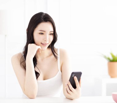 gülümseyen genç kadın oturuyor ve cep telefonu izlemek