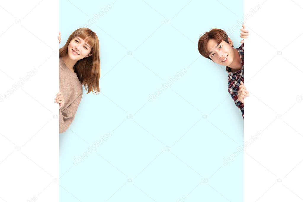 young couple posing  behind blank white board