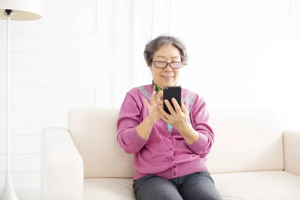 Старша Жінка Використовуючи Мобільний Телефон Сидячи Дивані — стокове фото