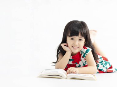 yerde yatarken kitap ile küçük kız gülümseyerek