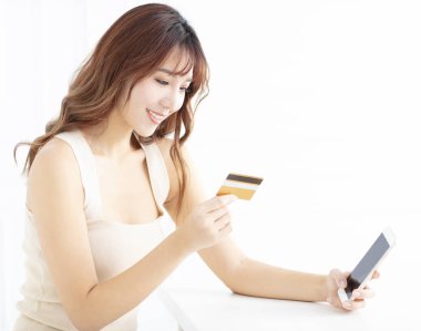 Genç kadın izlerken cep telefonu ve kredi kartı gülümseyen