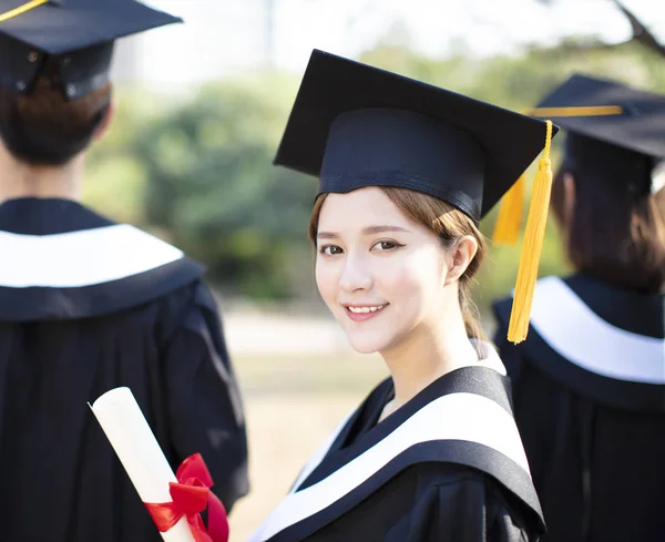 Smiling young woman at graduation showing her diploma — Stock Photo, Image