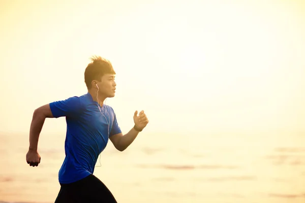 Joven hombre corriendo en la playa al atardecer — Foto de Stock