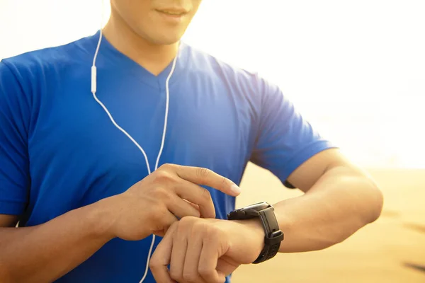 Молодий чоловік біжить на пляжі і перевіряє частоту серцевих скорочень Монітор — стокове фото
