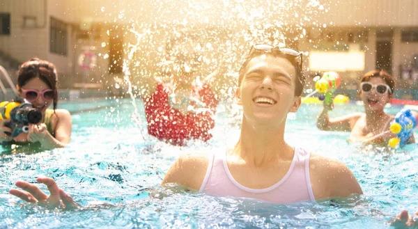 Glückliche Freunde spielen in den Sommerferien im Schwimmbad — Stockfoto