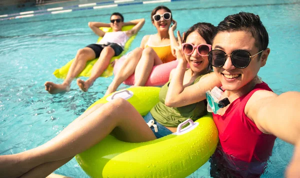 Jovens amigos felizes tomando selfie na piscina — Fotografia de Stock