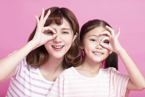Gelukkige moeder en dochter houden vingers in de buurt van ogen — Stockfoto