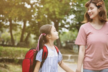 Anne ve çocuk okula giderken el ele tutuşuyor 