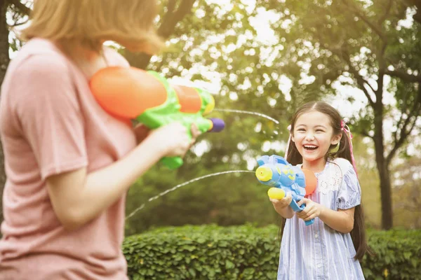 Mãe e meninas brincando de armas de água no parque — Fotografia de Stock