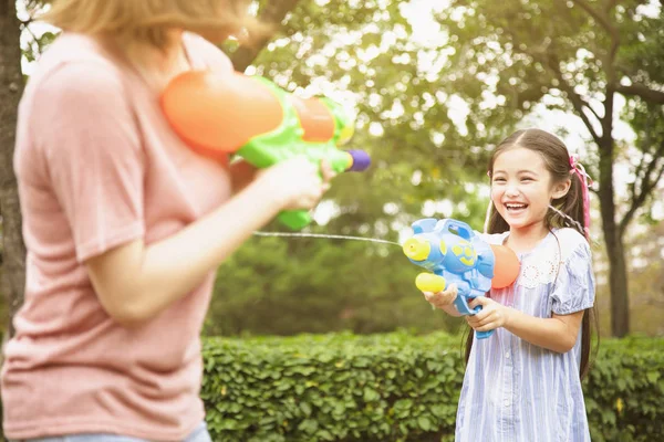 Mother and little girls playing water guns in the park — Stock Photo, Image