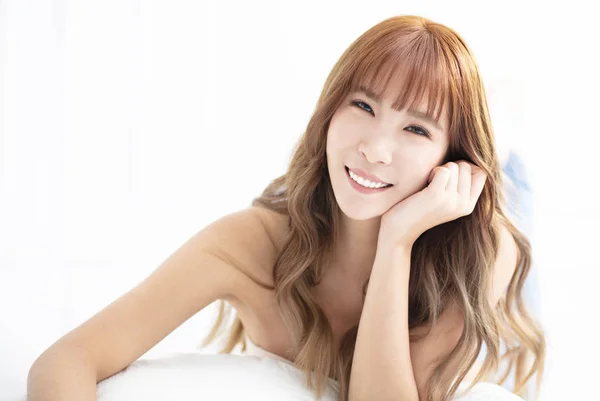 Young woman smiling and lying on bed — 스톡 사진