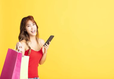 Alışveriş çantaları ve akıllı telefonlar tutan genç bir kadın.