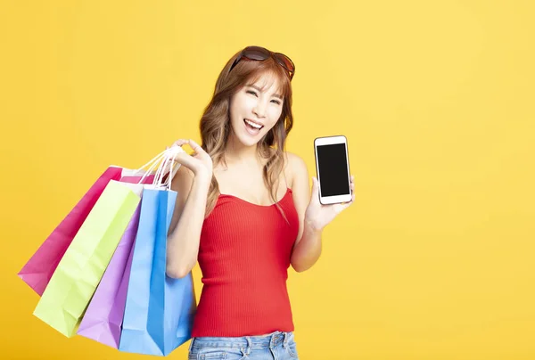 Mladá žena držící nákupní tašky a chytrý telefon — Stock fotografie