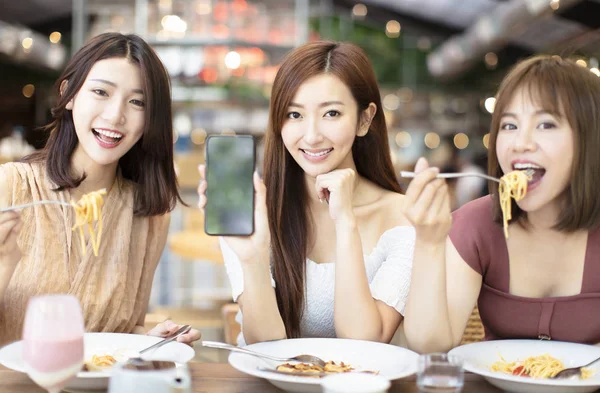 Happy friends having dinner and showing smarphone in restaur — стоковое фото