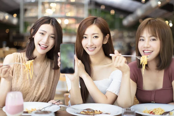 Amici felici che cenano e mostrano smartphone in restaura — Foto Stock