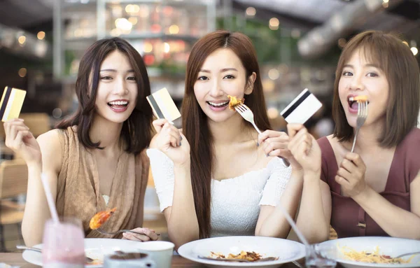 Amigos felices cenando y mostrando tarjeta de crédito en restaur —  Fotos de Stock