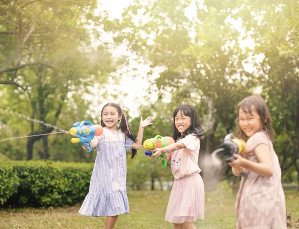 Fröhliche kleine Mädchen spielen im Sommer mit Wasserpistolen — Stockfoto