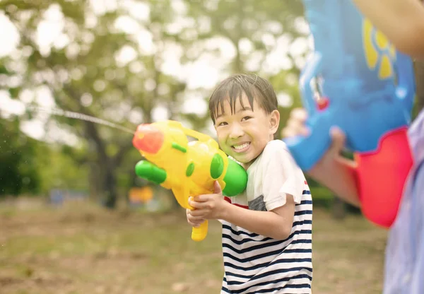 Szczęśliwy mały chłopiec grając z pistoletów wodnych na lato — Zdjęcie stockowe