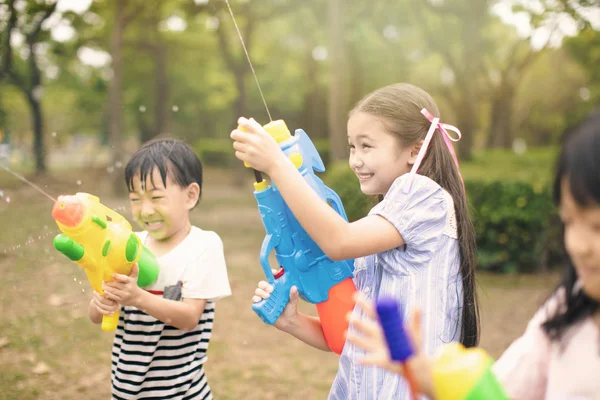 Crianças felizes brincando com armas de água no verão — Fotografia de Stock