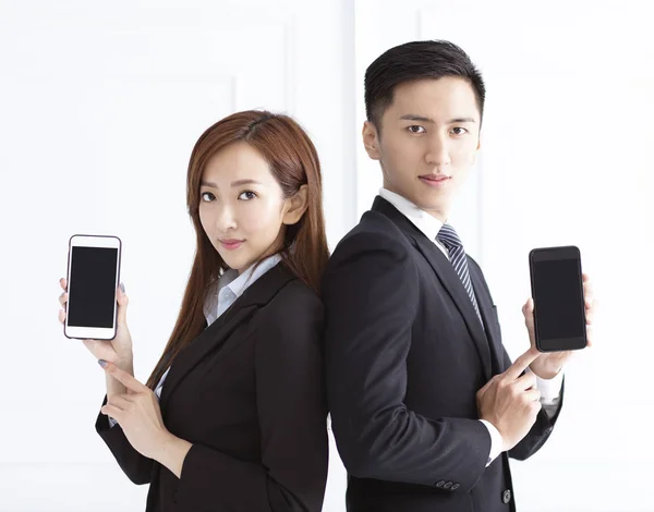 Young smiling businesswoman and businessman showing smart phone — ストック写真
