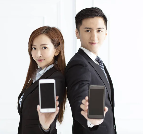 Young smiling businesswoman and businessman showing smart phone — ストック写真