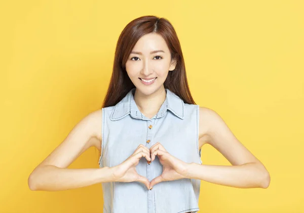 Sonriente joven mujer con forma de corazón signo de mano — Foto de Stock