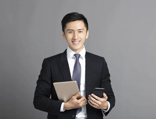 Joven hombre de negocios sosteniendo el teléfono inteligente y tableta pc —  Fotos de Stock