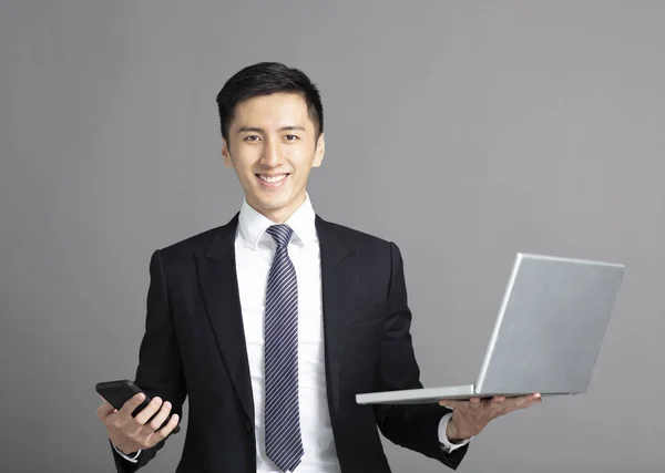 Jovem homem de negócios segurando telefone inteligente e tablet pc — Fotografia de Stock