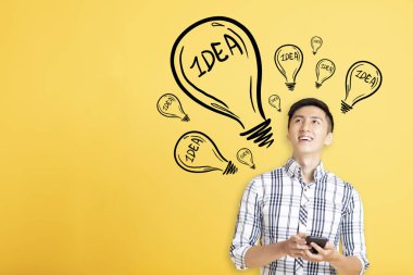 gülümseyen genç adam akıllı telefon kullanarak ve fikir işareti backgr görünümlü