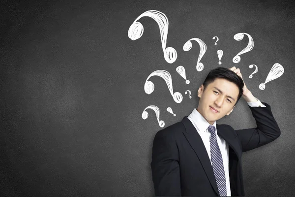 Confused young businessman scratching his head with question mar — Stock Photo, Image