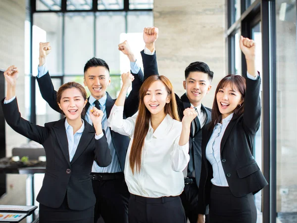 confident asian business team hands up and celebrating