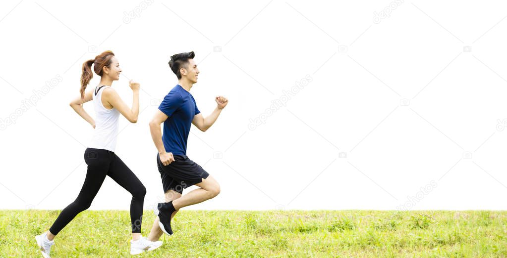 side view of young couple running on the grass