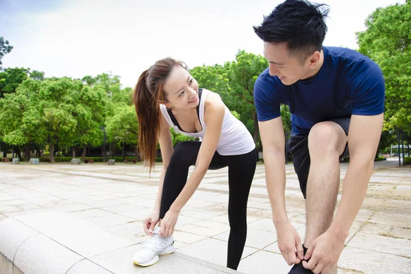 Pareja joven atando zapatillas y preparándose para correr —  Fotos de Stock