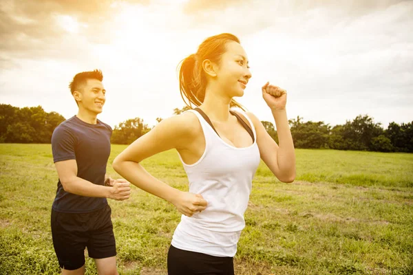 Pasangan muda yang bahagia joging dan berjalan di rumput — Stok Foto