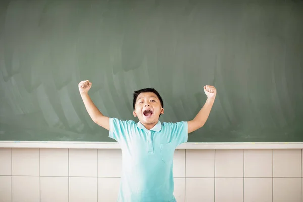 Niño de escuela feliz de pie contra el fondo de pizarra — Foto de Stock